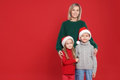 Photo of Mother and her little children on red background, space for text. Christmas season