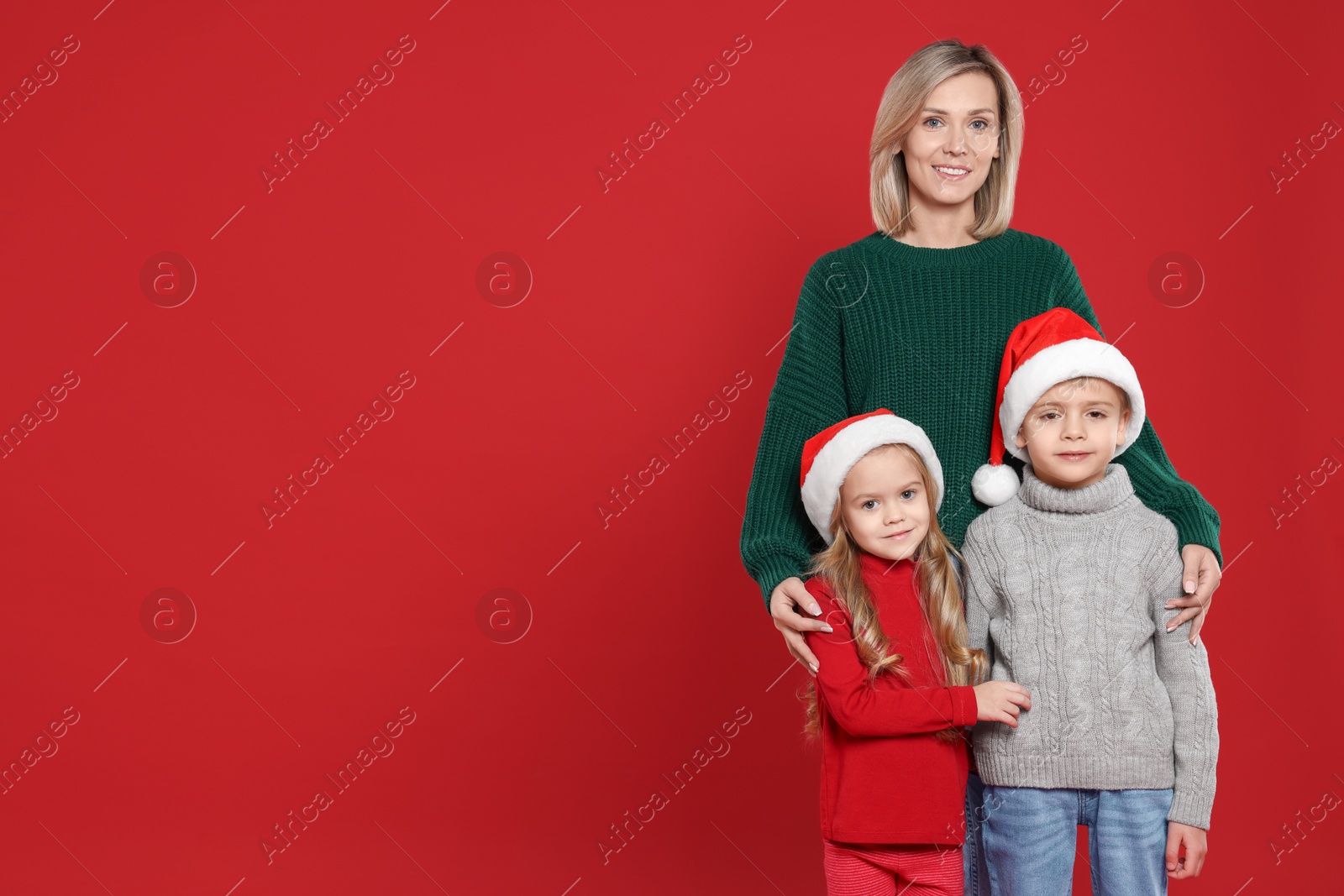 Photo of Mother and her little children on red background, space for text. Christmas season