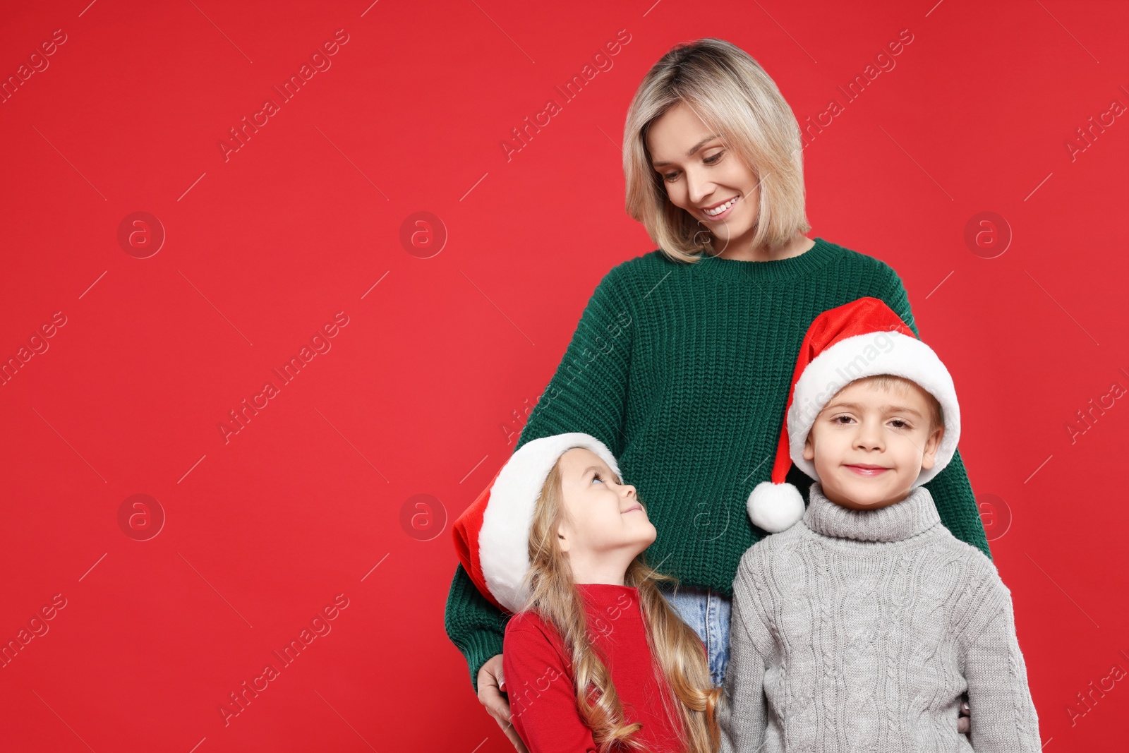 Photo of Mother and her little children on red background, space for text. Christmas season