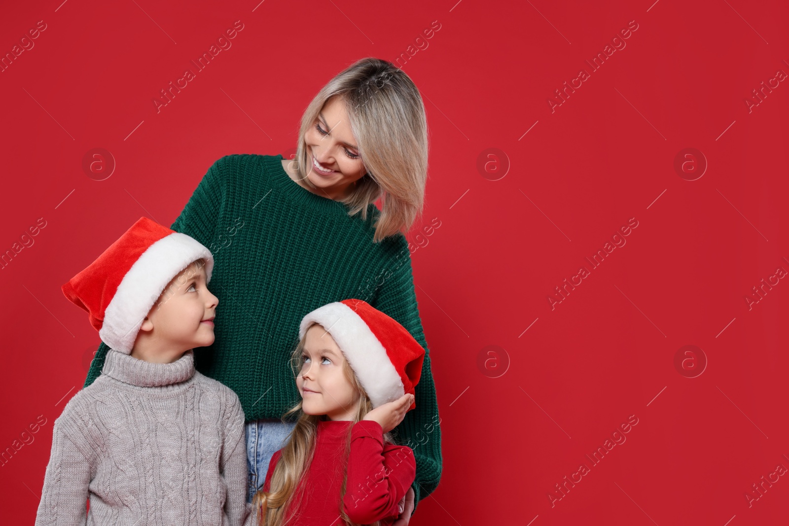 Photo of Mother and her little children on red background, space for text. Christmas season