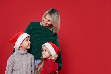 Photo of Mother and her little children on red background, space for text. Christmas season