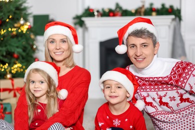 Photo of Lovely family in Christmas sweaters and Santa hats at home