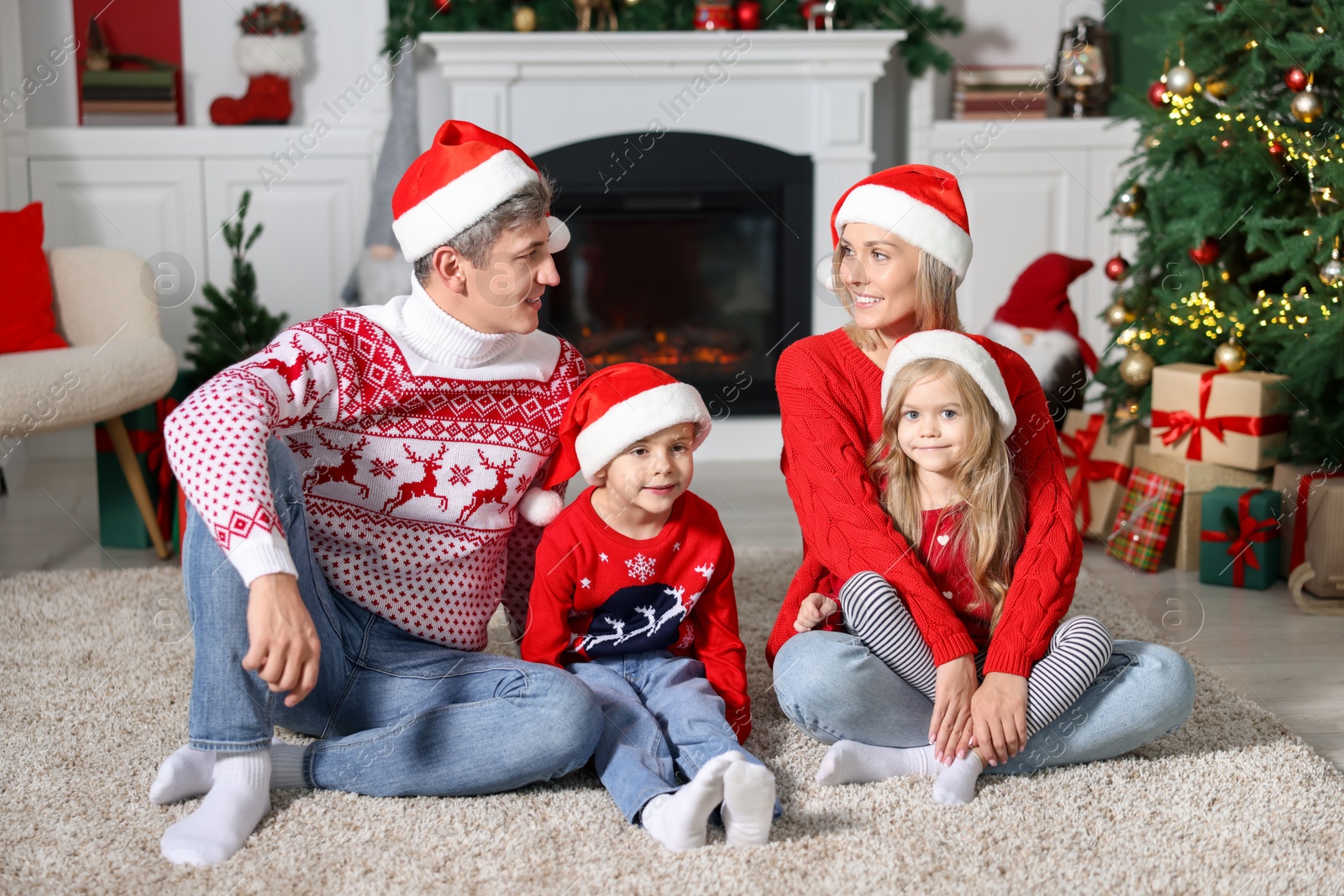 Photo of Lovely family in Christmas sweaters and Santa hats at home