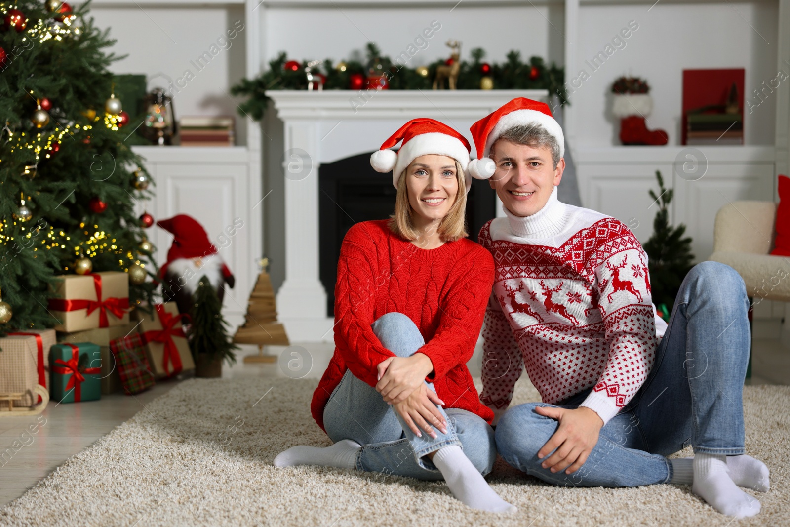 Photo of Lovely couple in Christmas sweaters and Santa hats at home