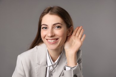 Photo of Woman showing hand to ear gesture on grey background