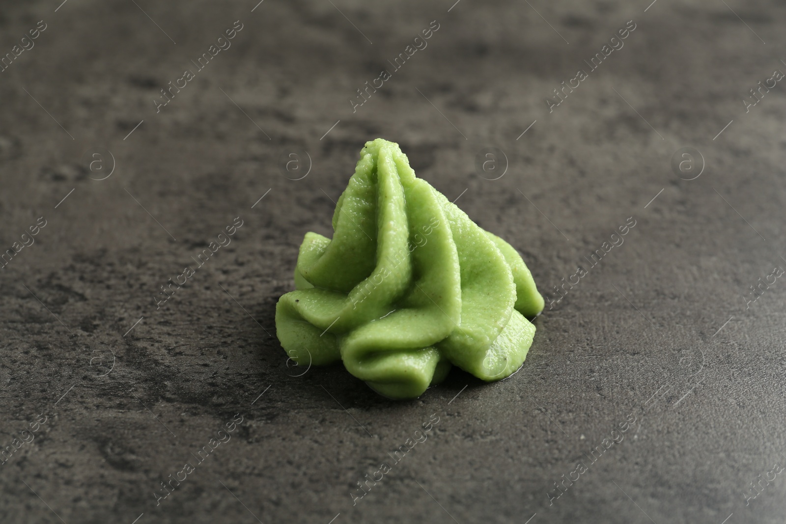 Photo of Hot wasabi paste on grey textured table, closeup