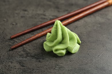 Photo of Hot wasabi paste and chopsticks on grey textured table, closeup