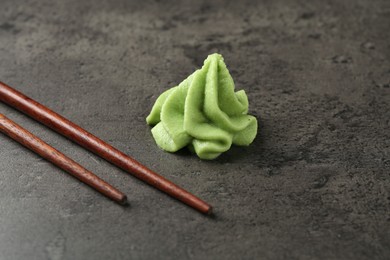 Photo of Hot wasabi paste and chopsticks on grey textured table, closeup