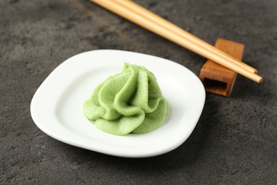 Photo of Hot wasabi paste and chopsticks on grey textured table, closeup