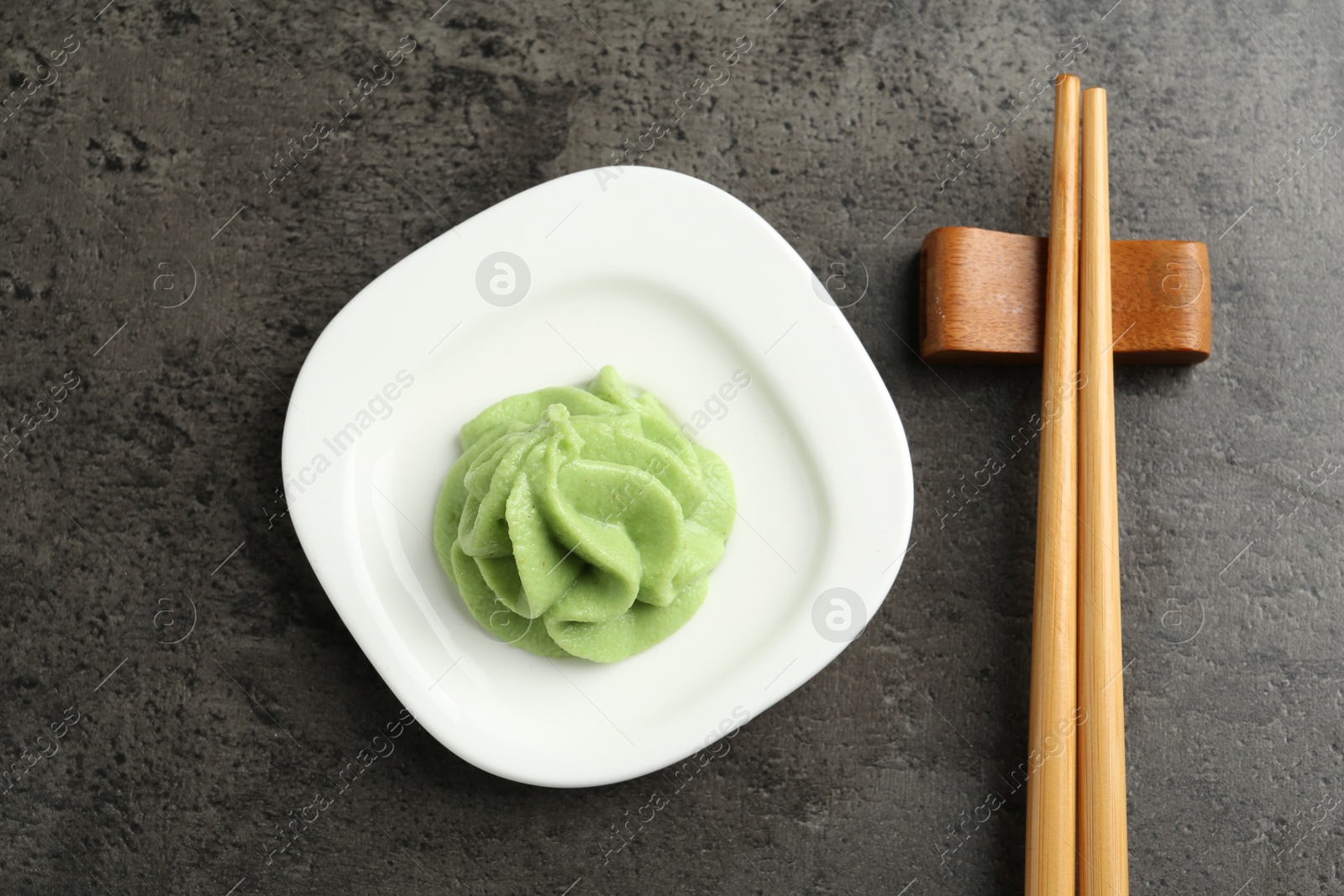 Photo of Hot wasabi paste and chopsticks on grey textured table, top view