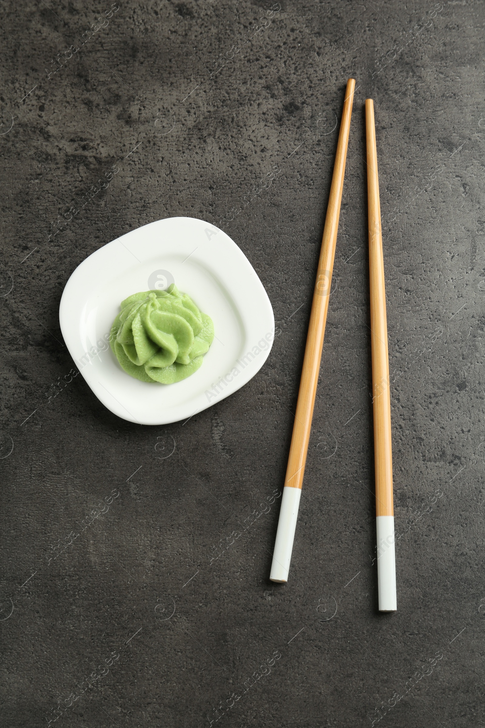 Photo of Hot wasabi paste and chopsticks on grey textured table, top view