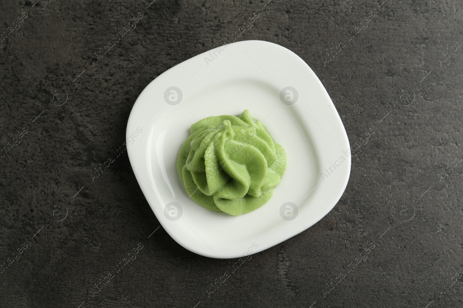 Photo of Plate with wasabi paste on grey textured table, top view