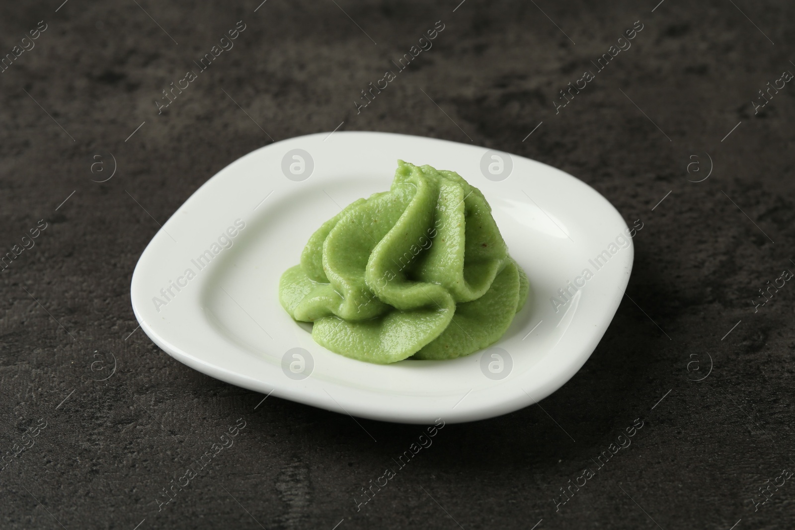 Photo of Plate with wasabi paste on grey textured table, closeup