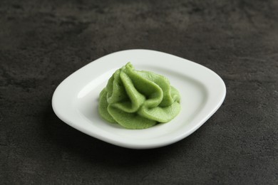 Photo of Plate with wasabi paste on grey textured table, closeup