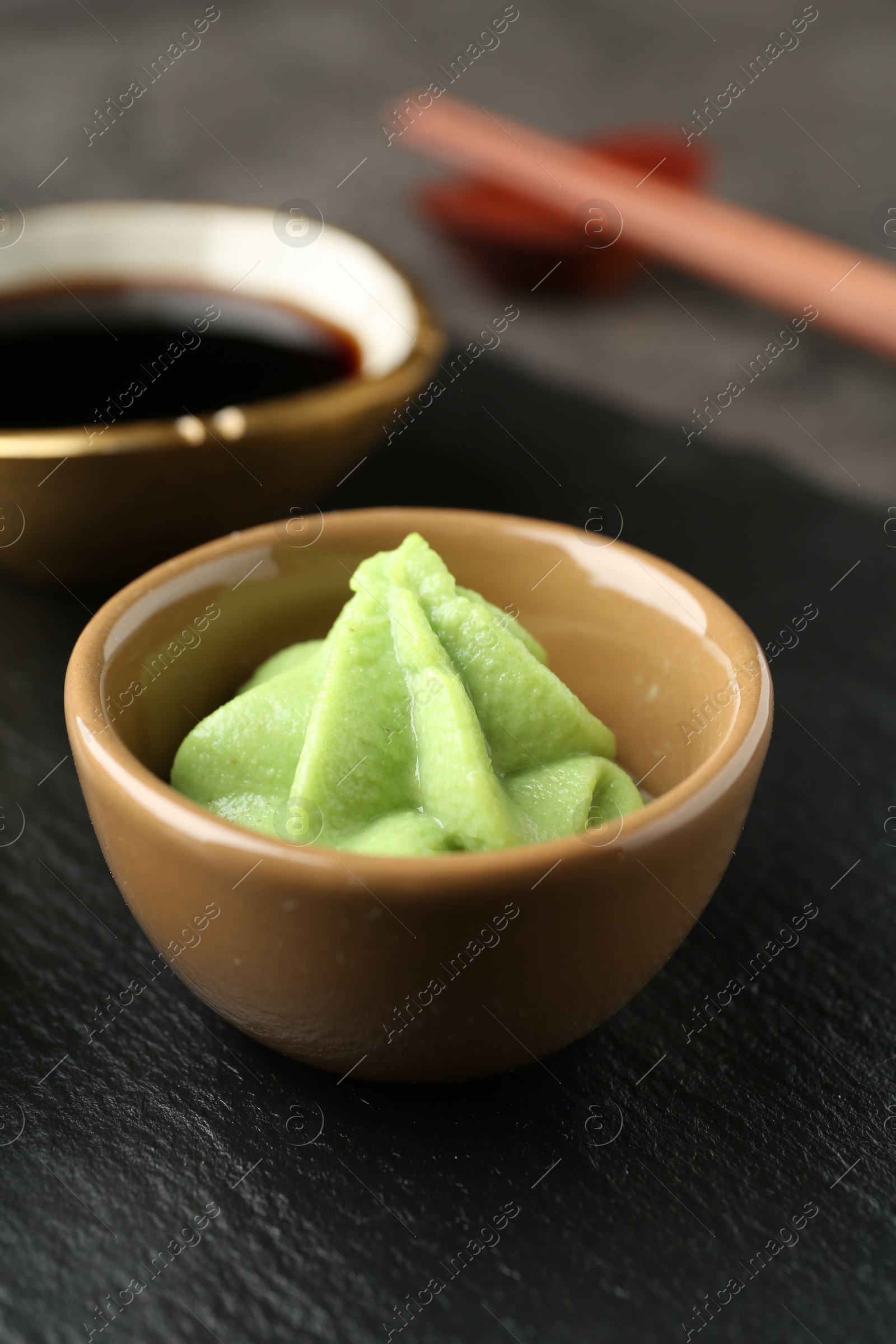 Photo of Hot wasabi paste and soy sauce on dark table, closeup