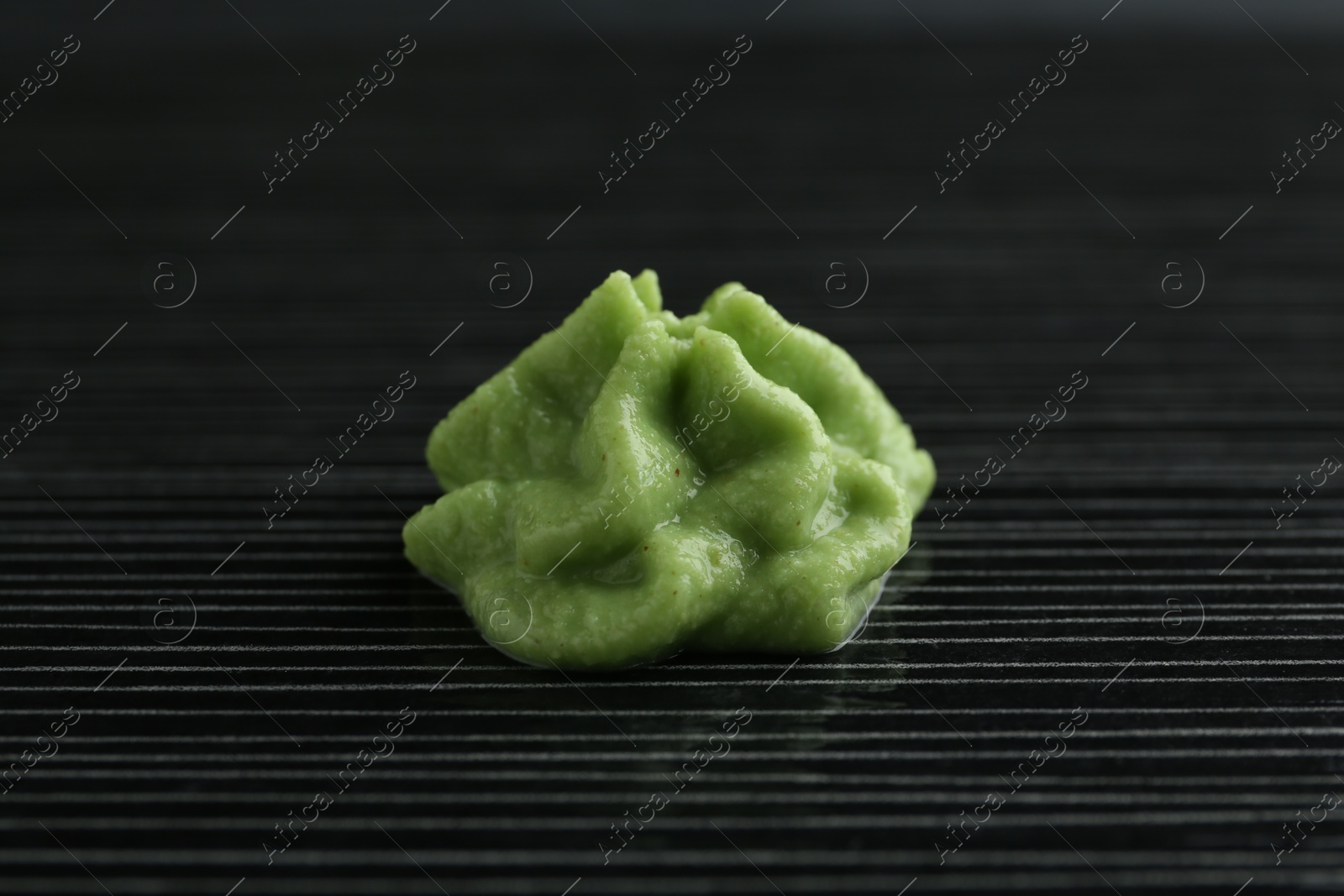 Photo of Hot wasabi paste on black textured table, closeup