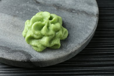 Photo of Marble board with hot wasabi paste on black textured table, closeup