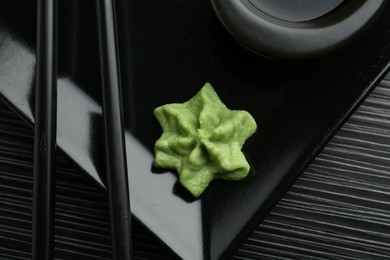 Hot wasabi paste and chopsticks on black textured table, top view