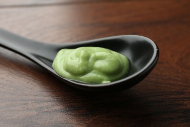 Photo of Spoon with hot wasabi paste on wooden table, closeup