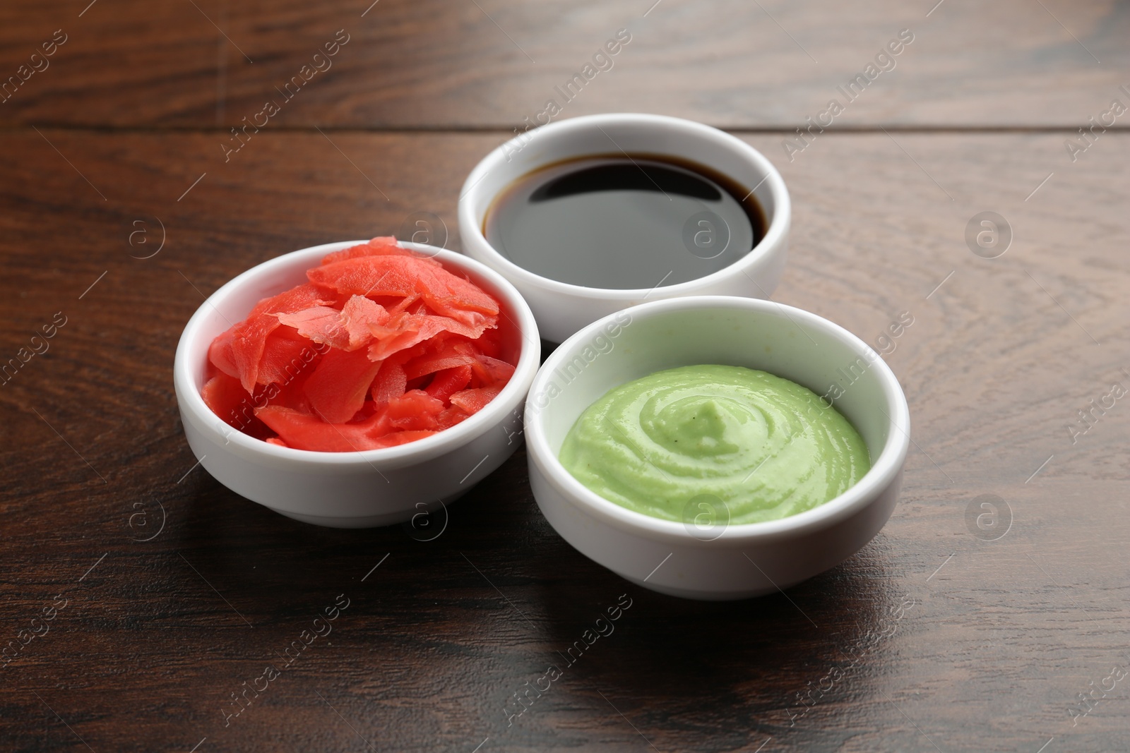 Photo of Hot wasabi paste, soy sauce and ginger on wooden table, closeup