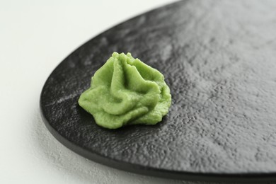 Photo of Slate board with hot wasabi paste on light textured table, closeup