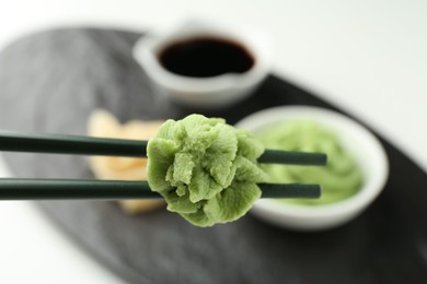 Photo of Chopsticks with hot wasabi paste on blurred background, closeup