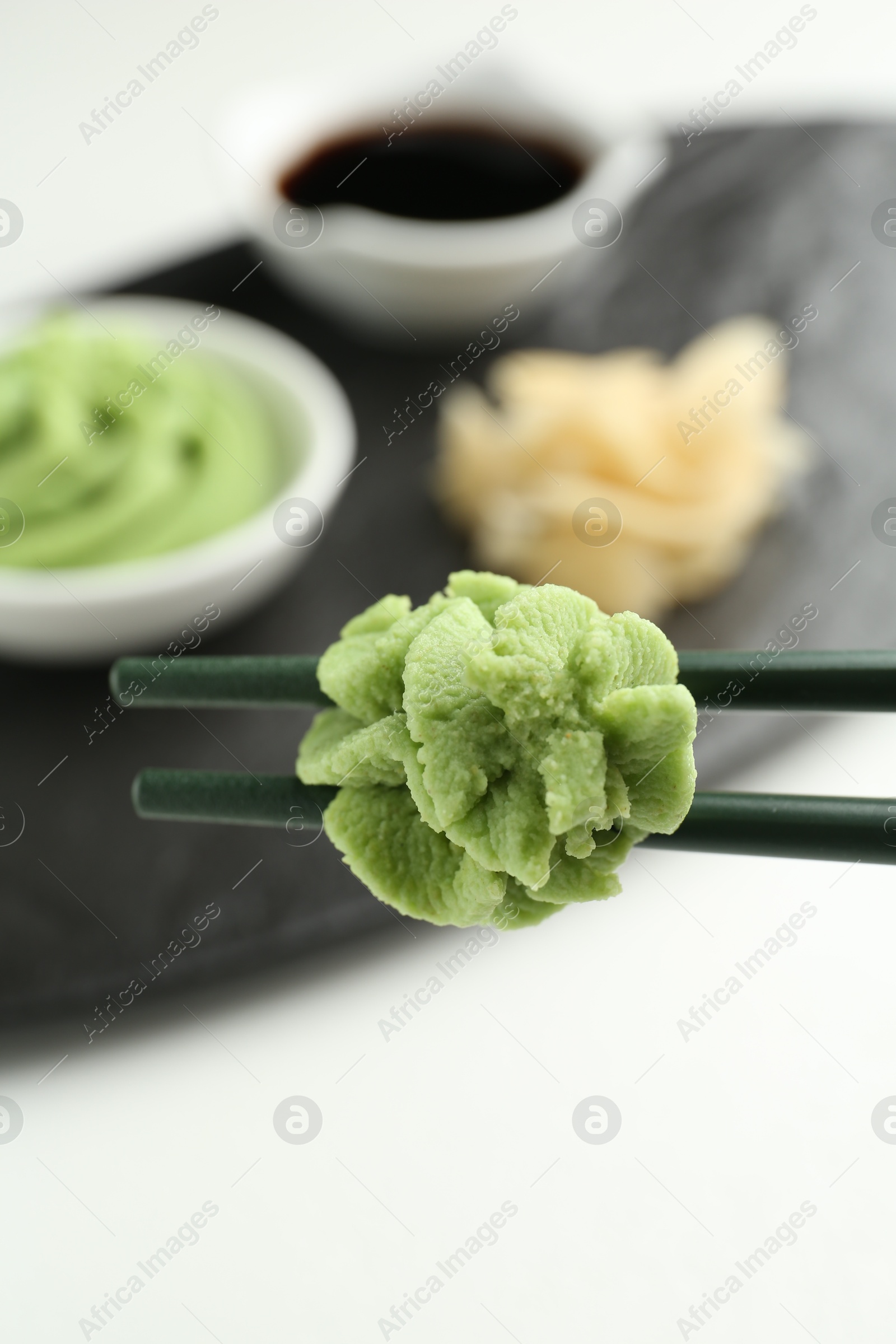 Photo of Chopsticks with hot wasabi paste on blurred background, closeup