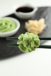 Photo of Chopsticks with hot wasabi paste on blurred background, closeup