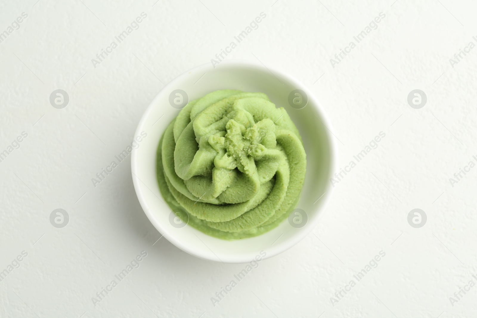 Photo of Hot wasabi paste in bowl on light textured table, top view