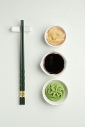 Photo of Hot wasabi paste, soy sauce, ginger and chopsticks on light textured table, flat lay