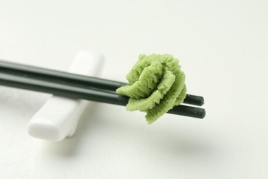 Photo of Chopsticks with hot wasabi paste on light textured table, closeup