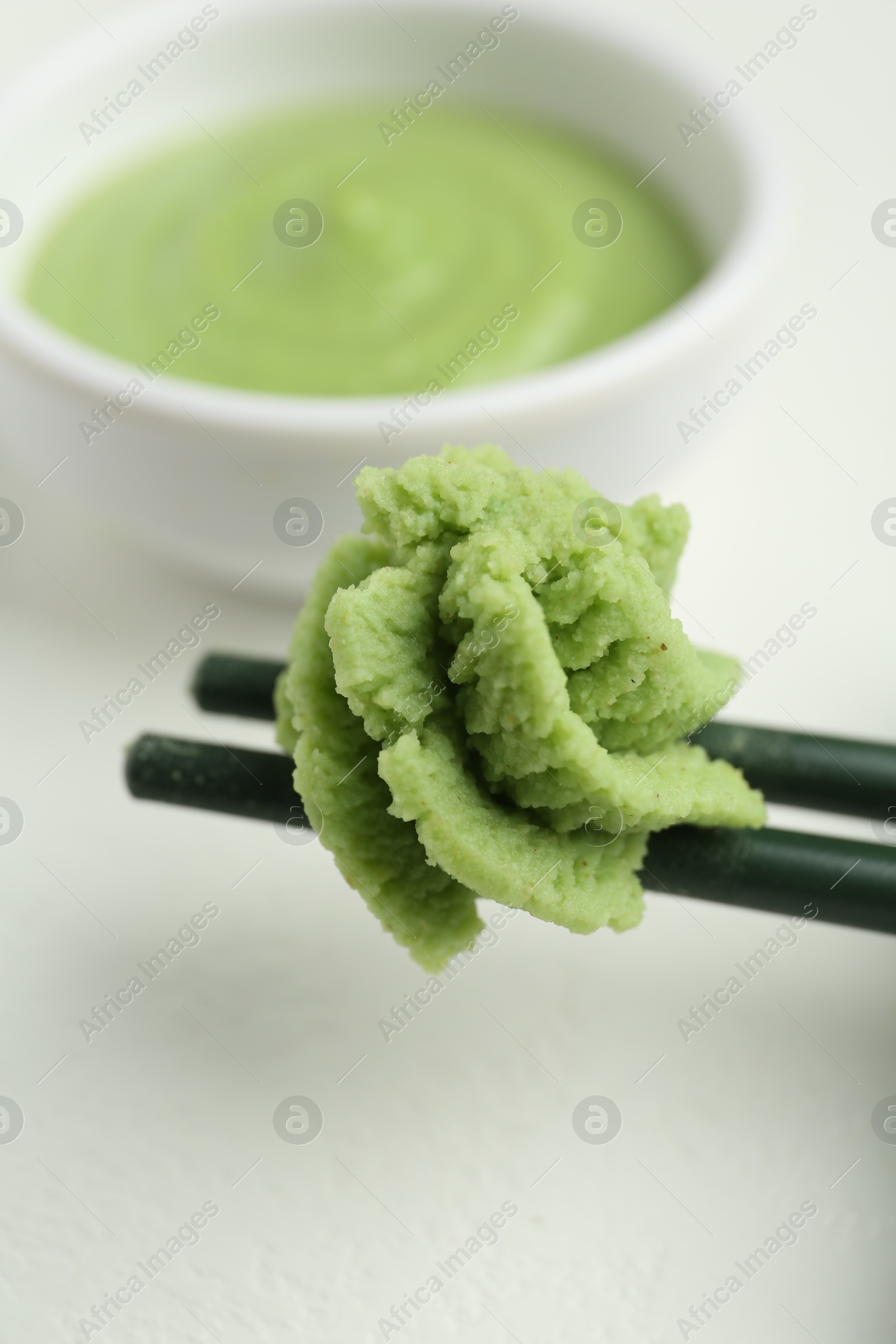 Photo of Chopsticks with hot wasabi paste on light table, closeup