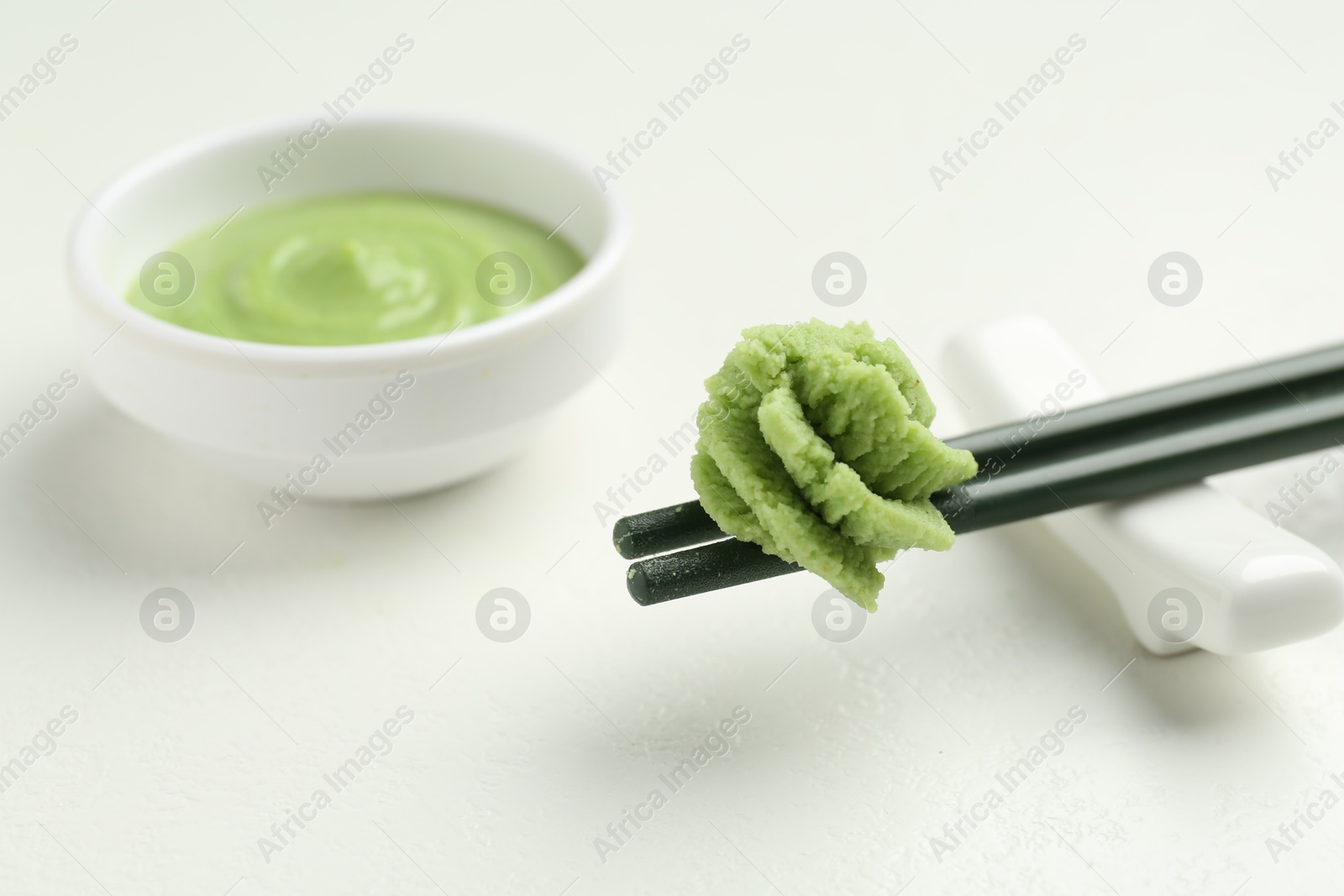 Photo of Chopsticks with hot wasabi paste on light textured table, closeup