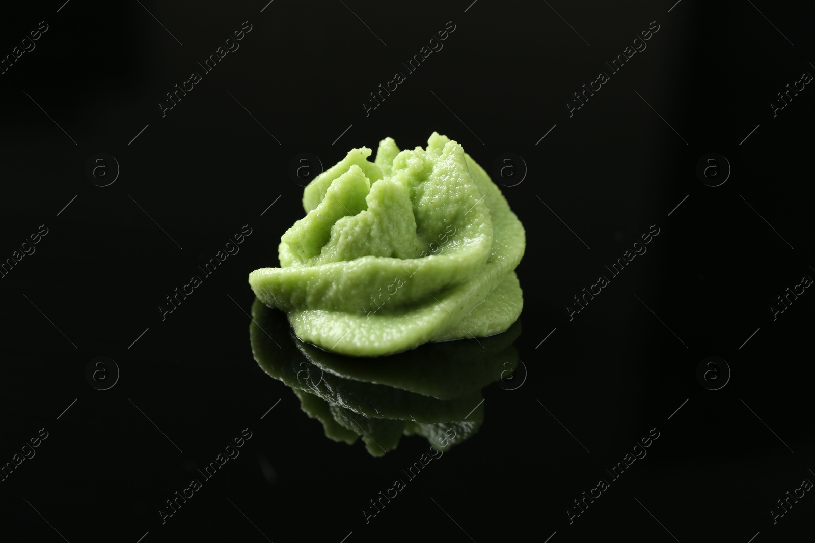 Photo of Hot wasabi paste on black mirror surface, closeup