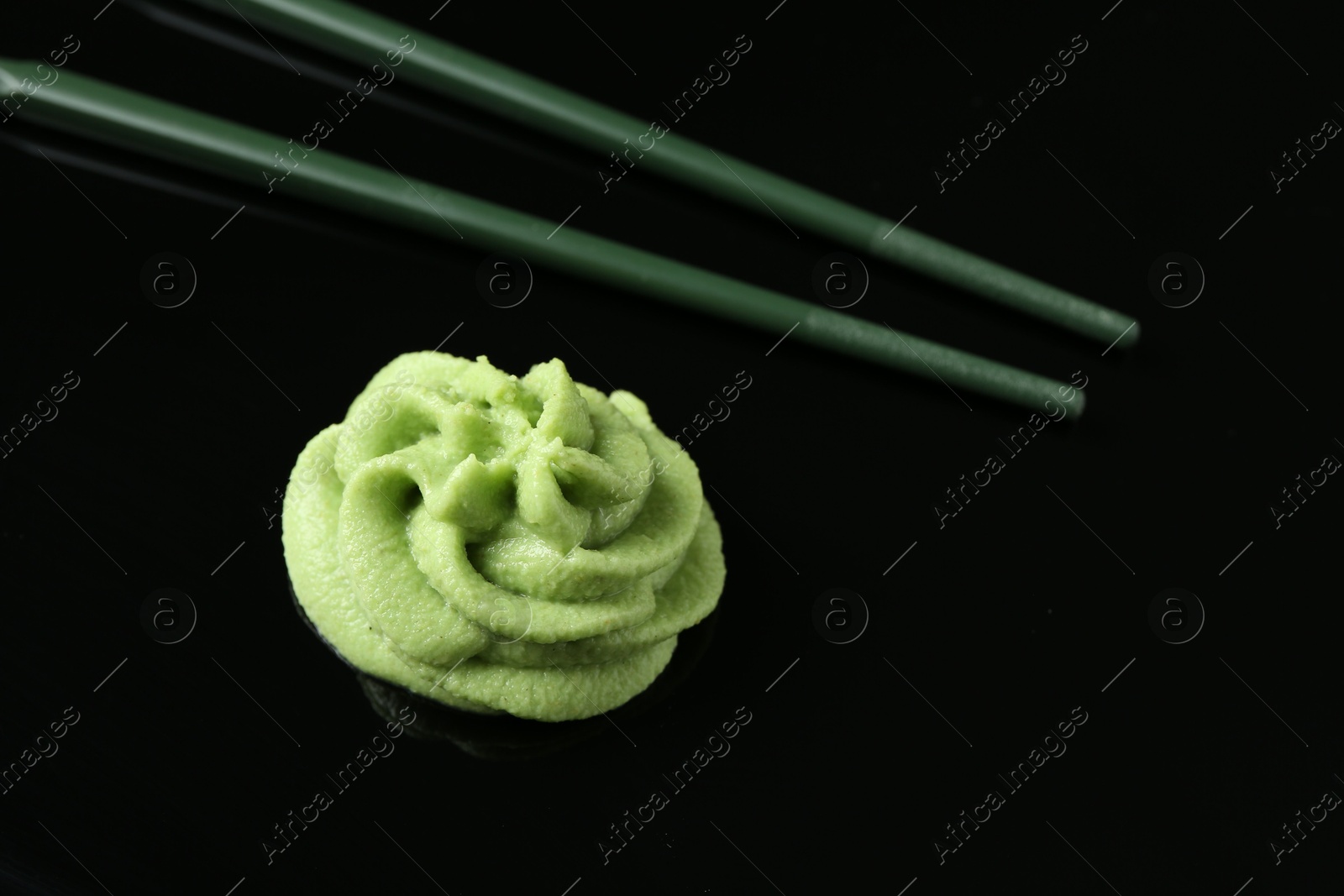 Photo of Hot wasabi paste and chopsticks on black background, closeup