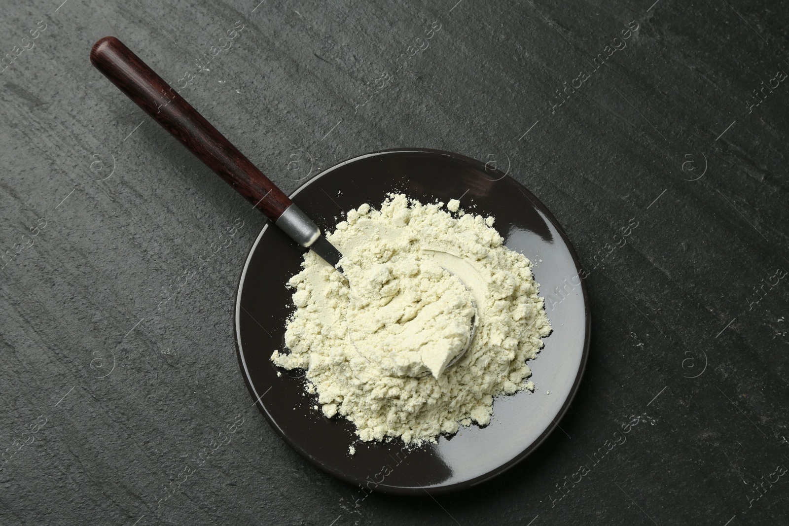 Photo of Plate with dry wasabi powder and spoon on dark textured table, top view