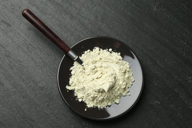 Photo of Plate with dry wasabi powder and spoon on dark textured table, top view