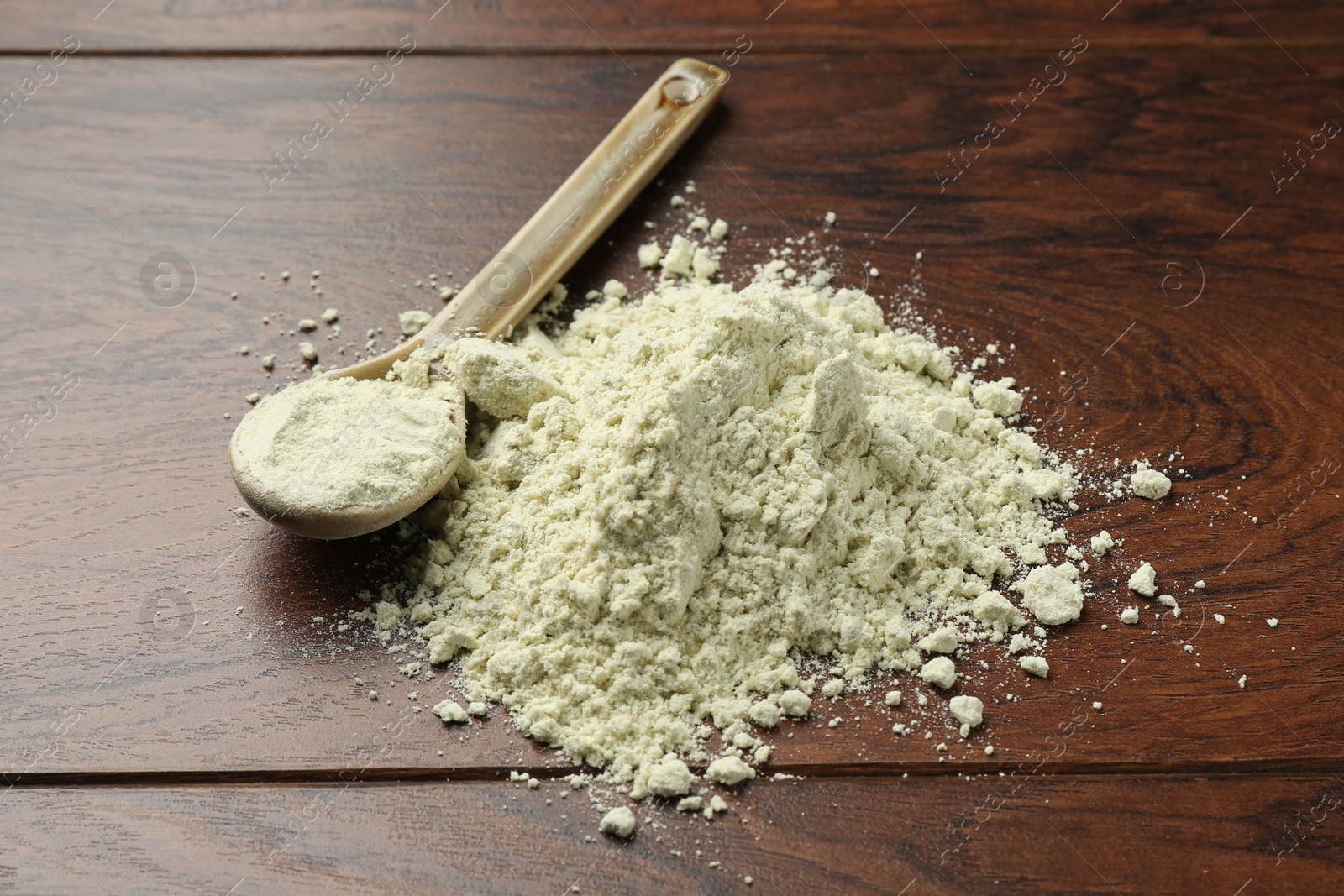 Photo of Pile of dry wasabi powder and spoon on wooden table, closeup