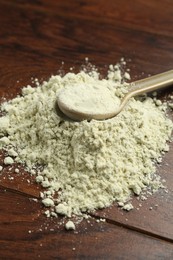 Photo of Pile of dry wasabi powder and spoon on wooden table, closeup