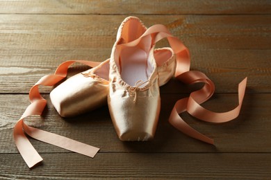 Photo of Pair of beautiful pointe shoes on wooden table