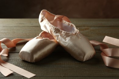 Photo of Pair of beautiful pointe shoes on wooden table, closeup