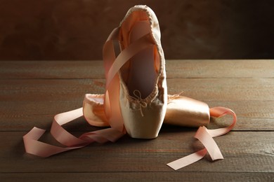 Photo of Pair of beautiful pointe shoes on wooden table