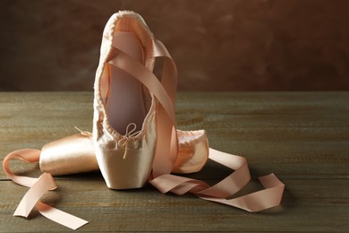 Photo of Pair of beautiful pointe shoes on wooden table. Space for text