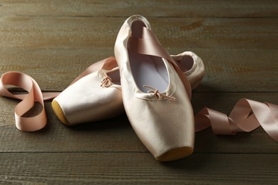 Photo of Pair of beautiful pointe shoes on wooden table