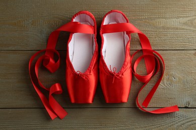 Photo of Pair of beautiful red pointe shoes on wooden background, top view