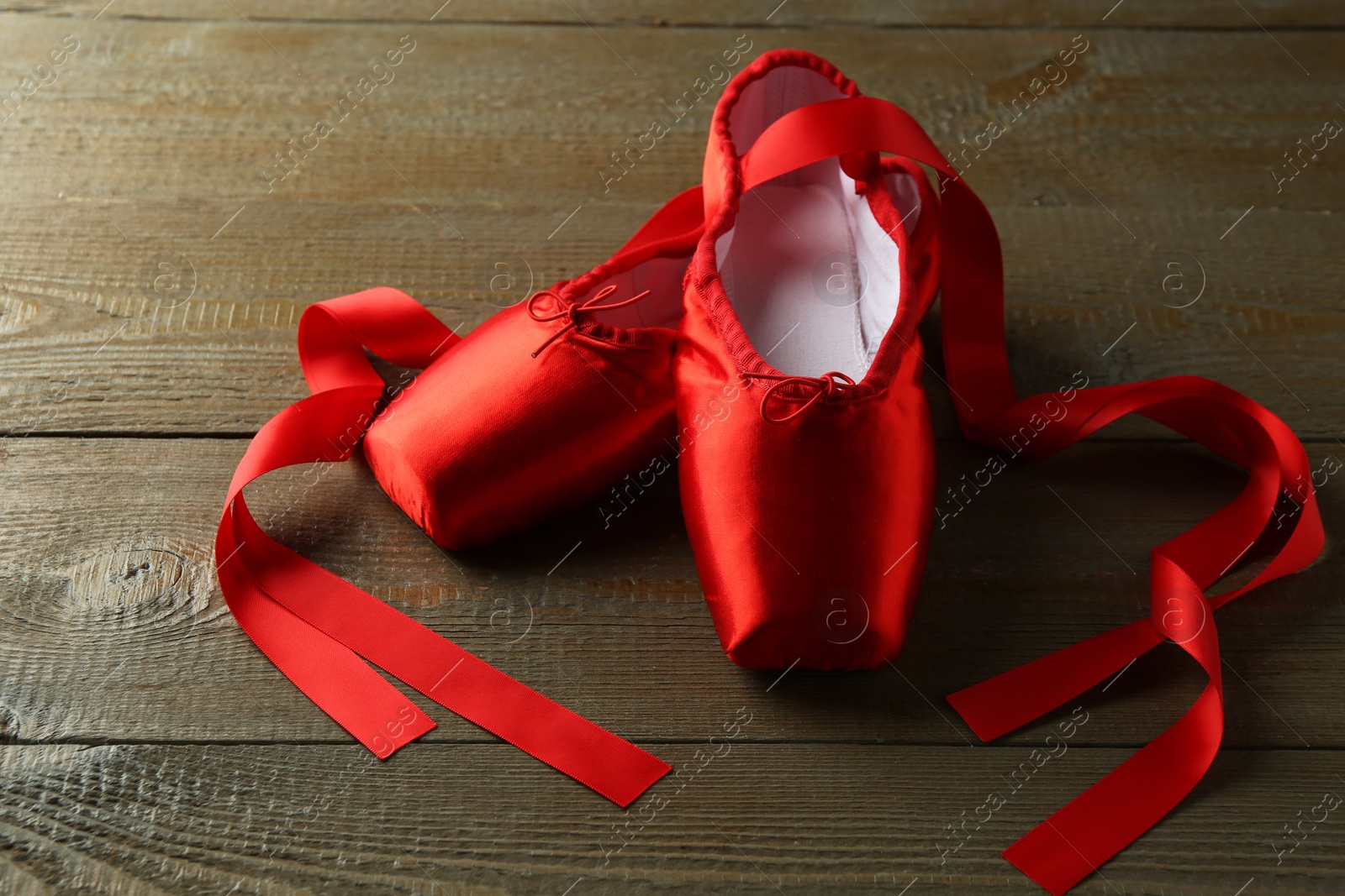 Photo of Pair of beautiful red pointe shoes on wooden table