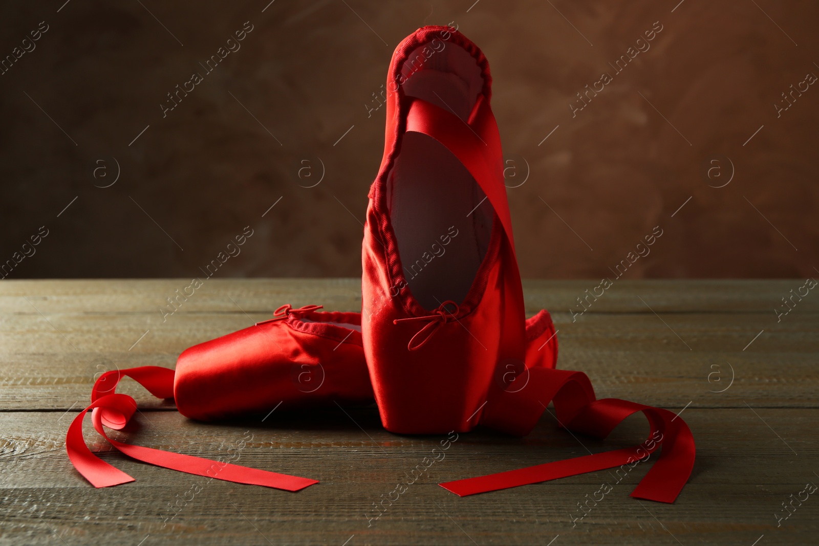 Photo of Pair of beautiful red pointe shoes on wooden table