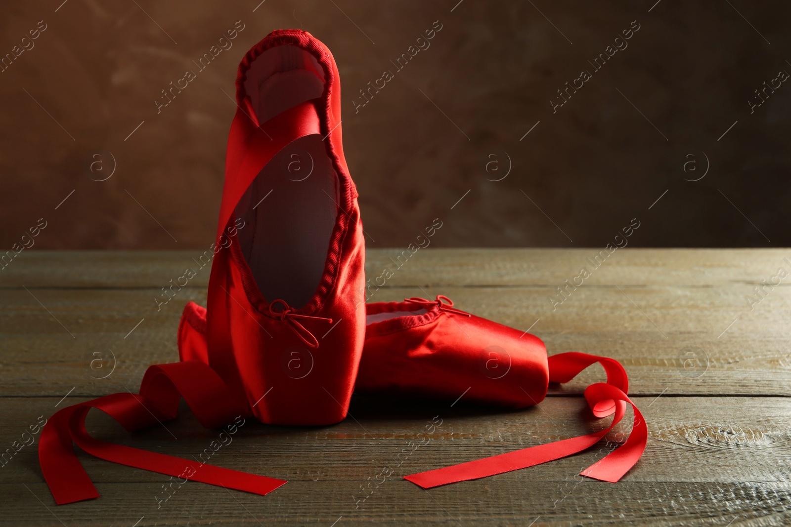 Photo of Pair of beautiful red pointe shoes on wooden table