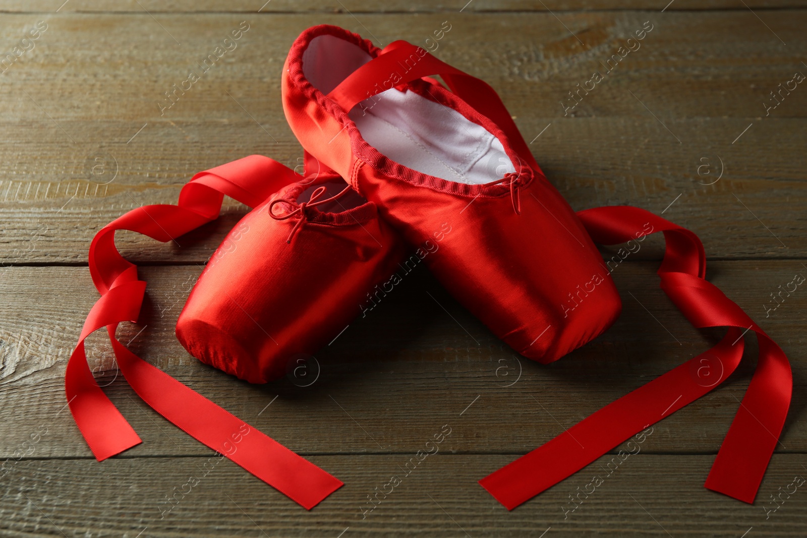 Photo of Pair of beautiful red pointe shoes on wooden table