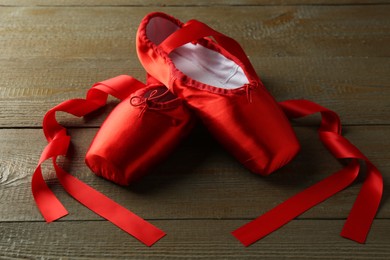 Photo of Pair of beautiful red pointe shoes on wooden table